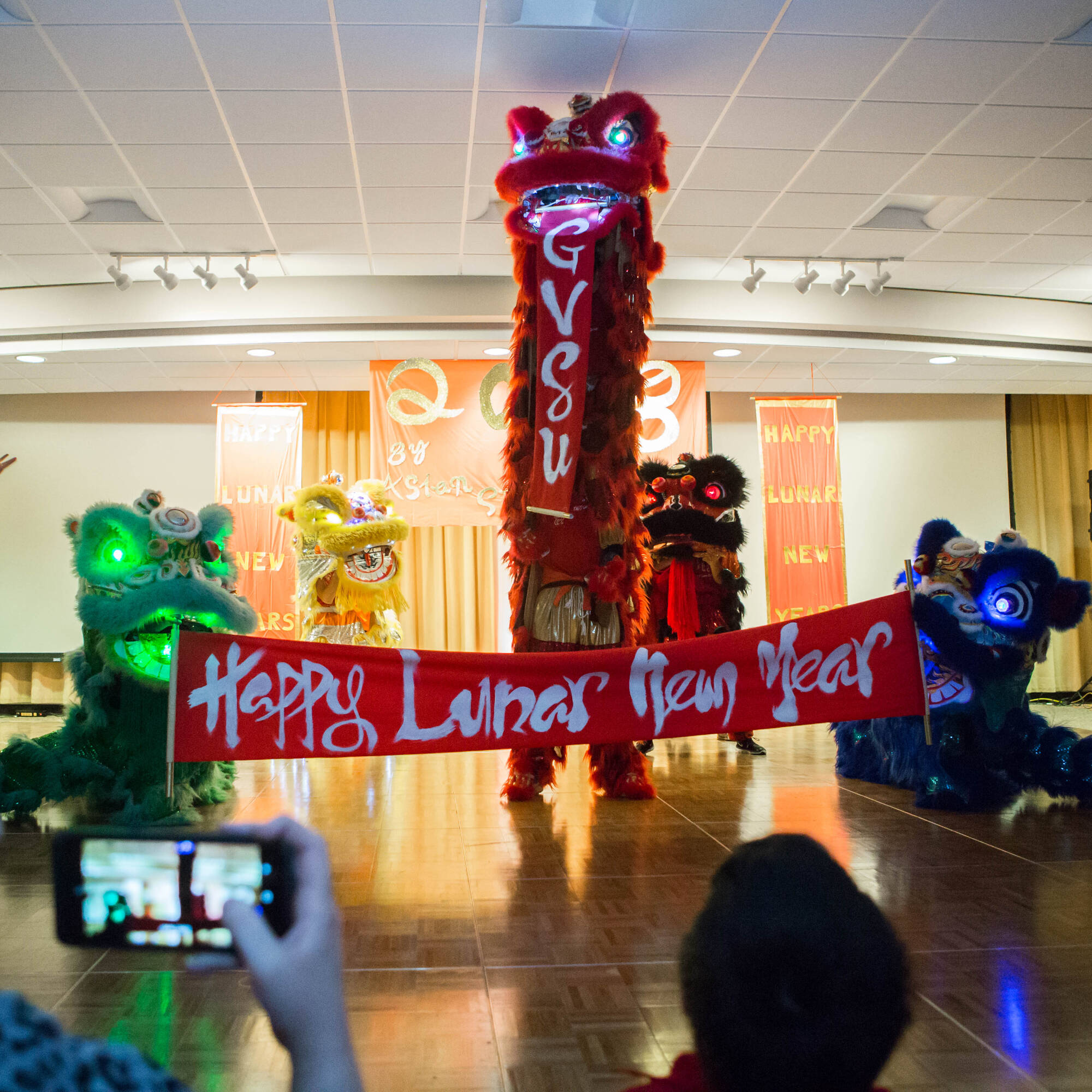 A group of performers in colorful lion costumes are performing a traditional lion dance on a stage.